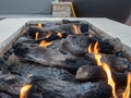 Close up of logs burning in a large, white, stone fire pit Royalty Free Stock Photo