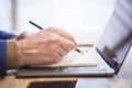 In close view, a man's hand writing down notes in a notepad on a laptop Royalty Free Stock Photo