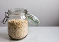 Close view of a glass jar filled with oatmeal flakes and a white background with copy space Royalty Free Stock Photo