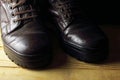 CLOSE VIEW OF A PAIR OF WORN COMBAT BOOTS WITH ON A WOODEN BOARD