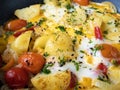 Pan full fried egg and boiled potatoes browned with vegetables and cherry tomatoes