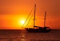 Close view of silhouette of sailing boat with sails down against sun at sunset, sun glare on sea waters. Romantic