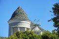 Close view of spire or turrent on house or home with gray roof tiles and white facade exterior with back yard trees and Royalty Free Stock Photo