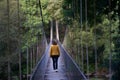 Close view of a woman in a yellow anorak walking on the suspension bridge with metal fence over the MiÃÂ±o river in Spain. Royalty Free Stock Photo
