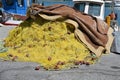 Close view on yellow fishing net with red-brown floats piled on pavement in port of Heraklion. Royalty Free Stock Photo
