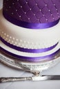 A close of a wedding cake with purple ribbon