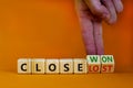 Close won or lost symbol. Businessman turns wooden cubes and changes words Close won to close lost. Beautiful orange background,