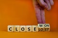 Close won or lost symbol. Businessman turns wooden cubes and changes words Close won to close lost. Beautiful orange background,