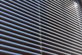 Closed aluminium roller blinds pattern and texture. Blue sky and rays of light in office window. Sunblind background Royalty Free Stock Photo