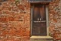 Closed ancient wooden door with red brick wall texture