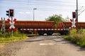 Closed barrier at the railroad crossing with red warning lights on, visible blurred red wagons in motion. Royalty Free Stock Photo