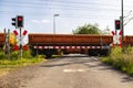 Closed barrier at the railroad crossing with red warning lights on, visible blurred red wagons in motion. Royalty Free Stock Photo