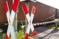 Closed barrier at the railway crossing with St. Andrew cross, visible blurred red wagon in motion.