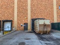 Closed bay doors and garbage roll-offs outside an industrial complex