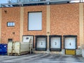 Closed bay doors and garbage roll-offs outside an industrial complex