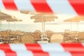 Closed beach. Sea, umbrellas and sunbeds with warning tape Royalty Free Stock Photo
