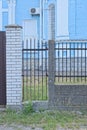 closed black metal door and part of the fence wall made of iron rods of gray stones Royalty Free Stock Photo