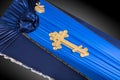 Closed blue coffin covered with cloth on gray background. coffin close-up with gold Church cross.