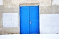 Closed blue painted door, gray plaster on wall, grunge background Royalty Free Stock Photo