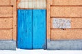 Closed blue painted door, pink plaster on wall, grunge background, winter snowy street Royalty Free Stock Photo