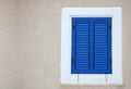 Closed blue window on white stucco wall, with vintage wooden jalousie, front view