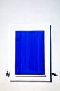 Closed blue window on a white wall in cycladic style Royalty Free Stock Photo