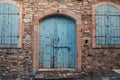 Closed blue wooden door and windows in old stone brick Cyprus building exterior Royalty Free Stock Photo