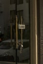 A closed board hanging just outside of a glass door and a chain with lock to ensure no one can enter. Selective focus
