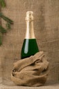 Closed bottle of champagne wine, against a background of coarse, brown fabric