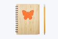 Closed bound notebook with a babmouk cover with an orange butterfly ornament on a white background and a yellow pencil Royalty Free Stock Photo