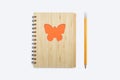 Closed bound notebook with a babmouk cover with an orange butterfly ornament on a white background and a yellow pencil Royalty Free Stock Photo