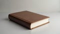 Closed brown book rests on plain grey surface. Features textured leather-like cover, clean white pages. Classic object represents Royalty Free Stock Photo