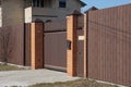 Closed brown gate and part of the fence of bricks and metal in the wall