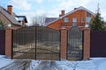 Closed brown gates and part of the fence in the street near the road in the snow Royalty Free Stock Photo