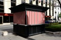 Closed brown wood street food kiosk with red and white striped painted boarded panels