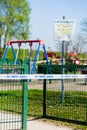 Closed children playground due to corona virus pandemic, with white tape across the gate