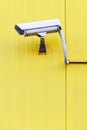 Surveillance camera on the exterior sandwich wall of a yellow building. Royalty Free Stock Photo