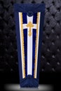 Closed coffin covered with blue and white cloth decorated with Church gold cross on gray background. Vertical position.