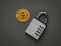 A closed combination lock and a large digital coin on a dark gray background. Flat lay Royalty Free Stock Photo