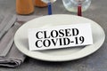 Closed Covid-19 written on a cardboard placed on a plate