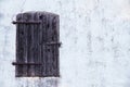 Closed dark brown wooden window with rusted metal hinges on a grungy white grey wall Royalty Free Stock Photo
