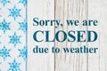 Closed due to weather sign with blue and white snowflakes on with weathered wood Royalty Free Stock Photo