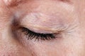 Closed eye and eyelashes with lumps of black ink mascara from an old seniior elderly woman