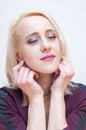 Closed eyes blonde woman holding earlobes with fingers Royalty Free Stock Photo