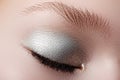 Closed eyes of young woman with shining sparkle makeup. Closeup