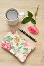 A closed flowery diary on a wooden table with a pink rose Royalty Free Stock Photo