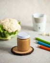 Closed glass jar with baby food cauliflower puree with fresh cauliflower and colored pencils. The concept of baby food
