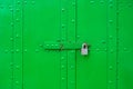 Closed green door riveted steel with a padlock.