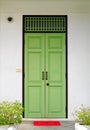 Closed green wooden doors with red welcome mat