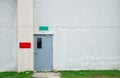 Closed grey door with green and red text box on white concrete wall Royalty Free Stock Photo